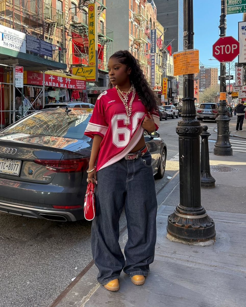 Person wearing a red sports jersey with the number 69 on a city street.